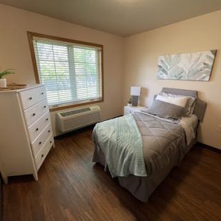 Cozy and well-lit bedroom featuring a single bed, stylish bedding, and a modern dresser.