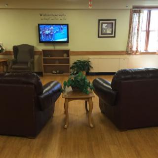 A cozy living room with leather chairs facing a television and a small table with a plant.
