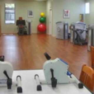 A rehabilitation room equipped with exercise machines and therapy balls.