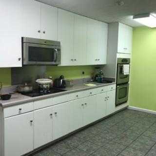 A modern kitchen featuring white cabinets, green walls, and various cooking appliances.