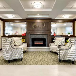 A cozy living room with patterned armchairs and a central fireplace, enhanced by elegant wood paneling and soft lighting.