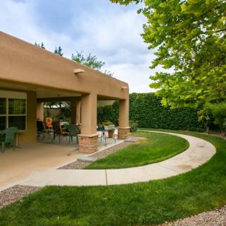 A serene backyard with a covered patio and well-maintained lawn.