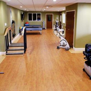 A spacious home gym with exercise equipment on a wooden floor.