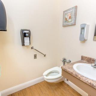A clean and organized bathroom with a toilet, sink, and dispensers.
