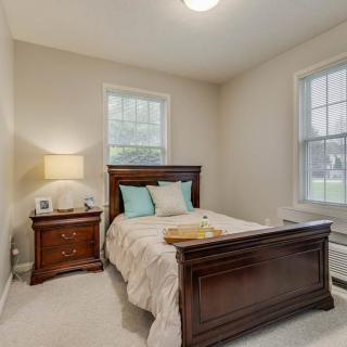 A cozy bedroom with a wooden bed and matching nightstand, softly lit by a lamp.