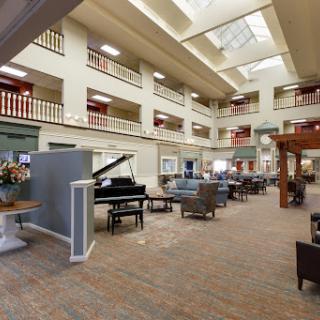 A spacious and elegantly designed interior lobby featuring comfortable seating, a grand piano, and ample natural light.
