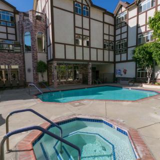 A residential apartment complex featuring a swimming pool and hot tub on a sunny day.
