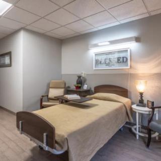 A clean and organized hospital room with a bed and seating area.
