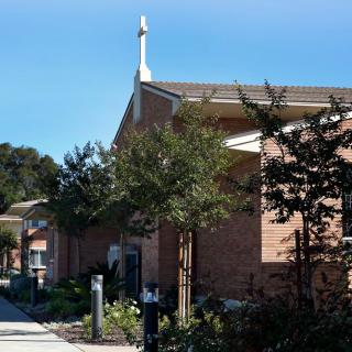 A church building with a steeple, surrounded by trees.