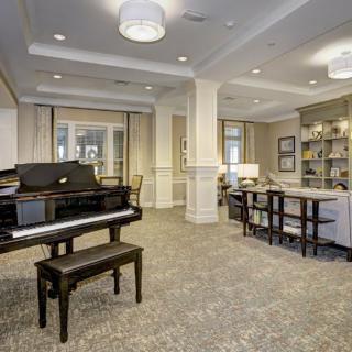A spacious lobby with a grand piano, cozy seating area, and library shelves.