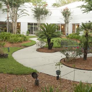 A beautifully landscaped garden with a winding pathway surrounded by lush greenery and adjacent to a building.