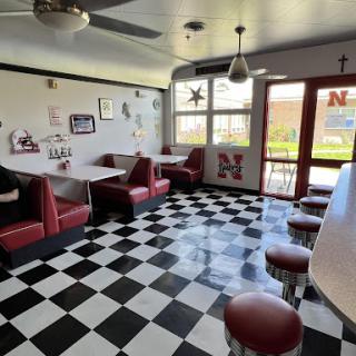 A cozy diner interior with booth seating and a classic checkered floor design.