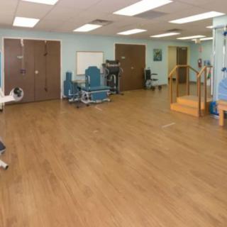 A spacious physical therapy room equipped with rehabilitation equipment and exercise tools.