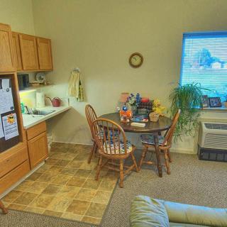 A cozy living area featuring a small dining table with chairs, a television, built-in cabinets, and an indoor plant.