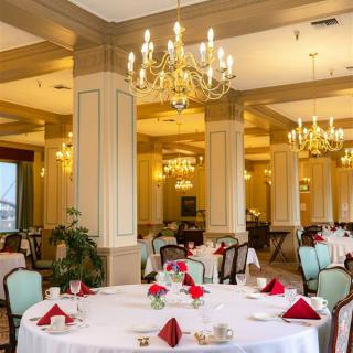 An elegant dining room with chandeliers and formally set tables.