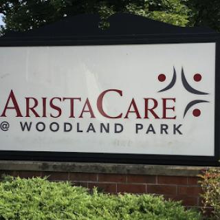 Signage for AristaCare at Woodland Park, indicating a healthcare facility.
