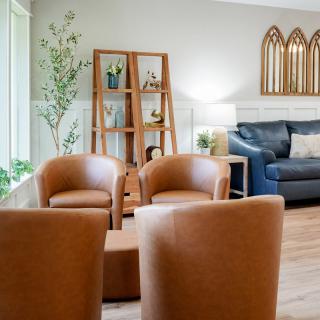 A cozy living room with brown chairs and a navy sofa, complemented by plants and decorative elements.