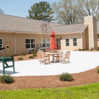 A cozy backyard patio with outdoor seating and an umbrella in a well-maintained garden.