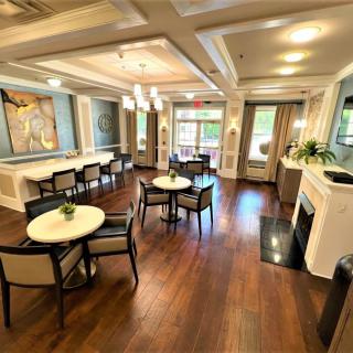 A well-decorated living area featuring tables, chairs, a fireplace, and artwork on the walls.