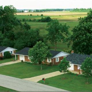Aerial view of suburban homes surrounded by greenery and open fields.