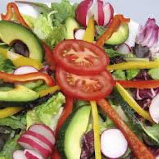 A vibrant and fresh vegetable salad with tomatoes, avocados, and radishes.