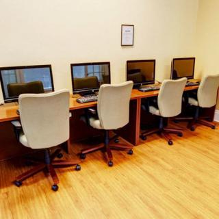 A row of computers with chairs in a workspace setting.