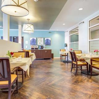 A modern dining area with neatly arranged tables and chairs, featuring elegant lighting and a wooden floor.