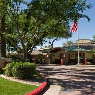 A landscaped driveway leading to a building with an American flag.