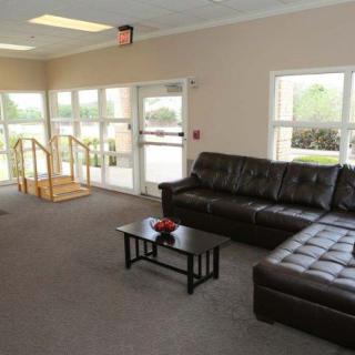 A spacious living room with a leather sofa and coffee table, featuring large windows that allow natural light to fill the space.