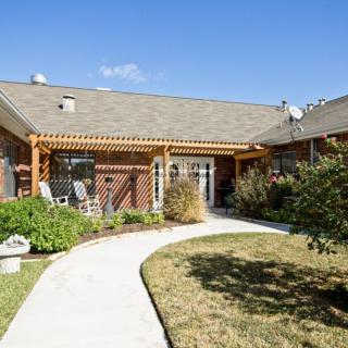 A suburban house with a pathway leading through a well-maintained garden on a sunny day.
