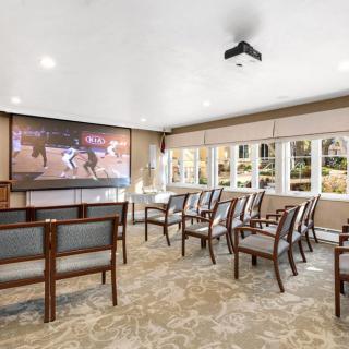 A comfortable home theater room with chairs facing a large screen and projector.