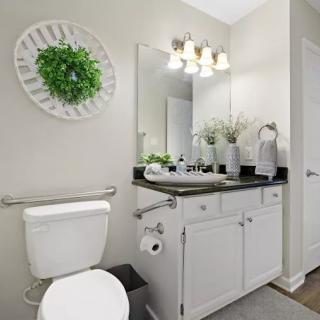 A modern bathroom with a white vanity, greenery decor, and bright lighting.