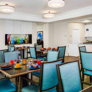 A modern dining area with neatly arranged tables and chairs, featuring colorful table settings and contemporary decor.