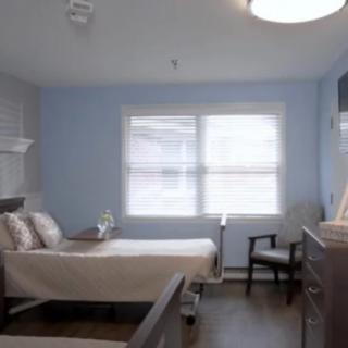 A hospital room featuring a bed, window, and seating area.
