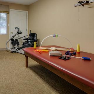 A physical therapy room equipped with a treatment table and exercise bike.