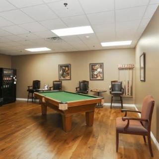 A cozy game room featuring a pool table with wooden flooring and comfortable seating.