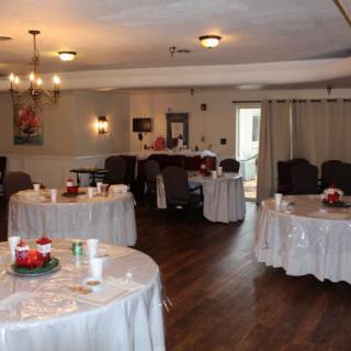 A decorated indoor banquet hall with round tables covered in white tablecloths.