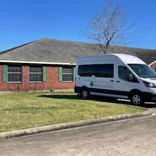 A parked van in front of a brick house on a clear day.
