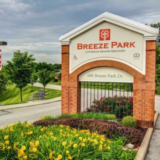Entrance sign to Breeze Park with well-maintained landscaping and flowers.