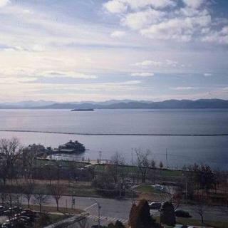A scenic view of a lake with distant mountains under a cloudy sky.