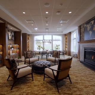 A cozy lounge area featuring modern furnishings and a warm fireplace, bathed in natural light.