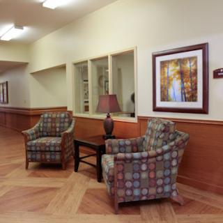 A cozy waiting area featuring two patterned chairs, a coffee table, and decorative artwork on the wall.