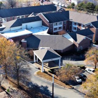 Aerial view of a large building complex surrounded by trees during autumn.