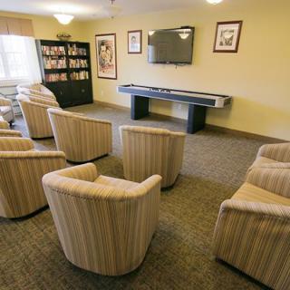 A cozy living room with multiple chairs arranged in front of a television and a bookshelf.