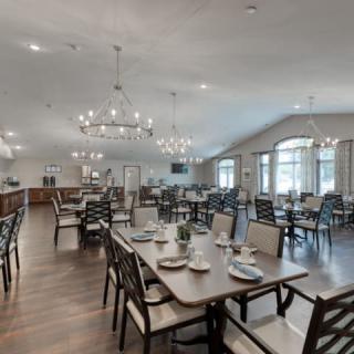 Spacious dining area with elegant chandeliers and neatly arranged tables and chairs.