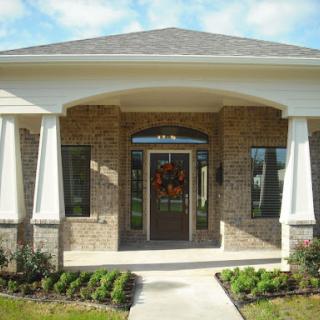 A welcoming entryway to a modern residential house with a brick facade and well-maintained landscaping.
