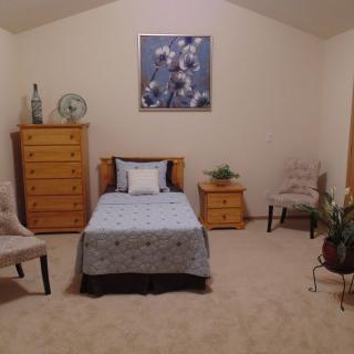 A cozy bedroom with a single bed, wooden furniture, and decorative elements.