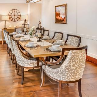 A beautifully arranged dining room with a wooden table and elegant patterned chairs.