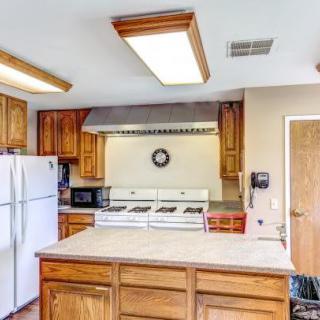 A spacious kitchen with wooden cabinets, a large refrigerator, and a central island.