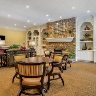 A cozy living room interior with a brick fireplace, surrounded by shelves and a seating area.